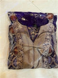 Decorative garment with intricate patterns in clear plastic packaging on a light background