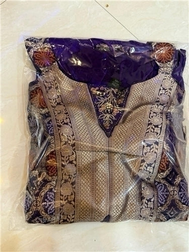 Decorative garment with intricate patterns in clear plastic packaging on a light background