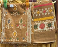 Brown fabric with floral embroidery displayed on a stand