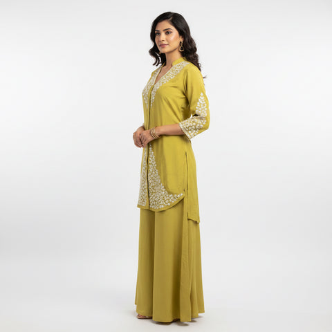Mannequin wearing a yellow outfit with intricate detailing in a room setting.